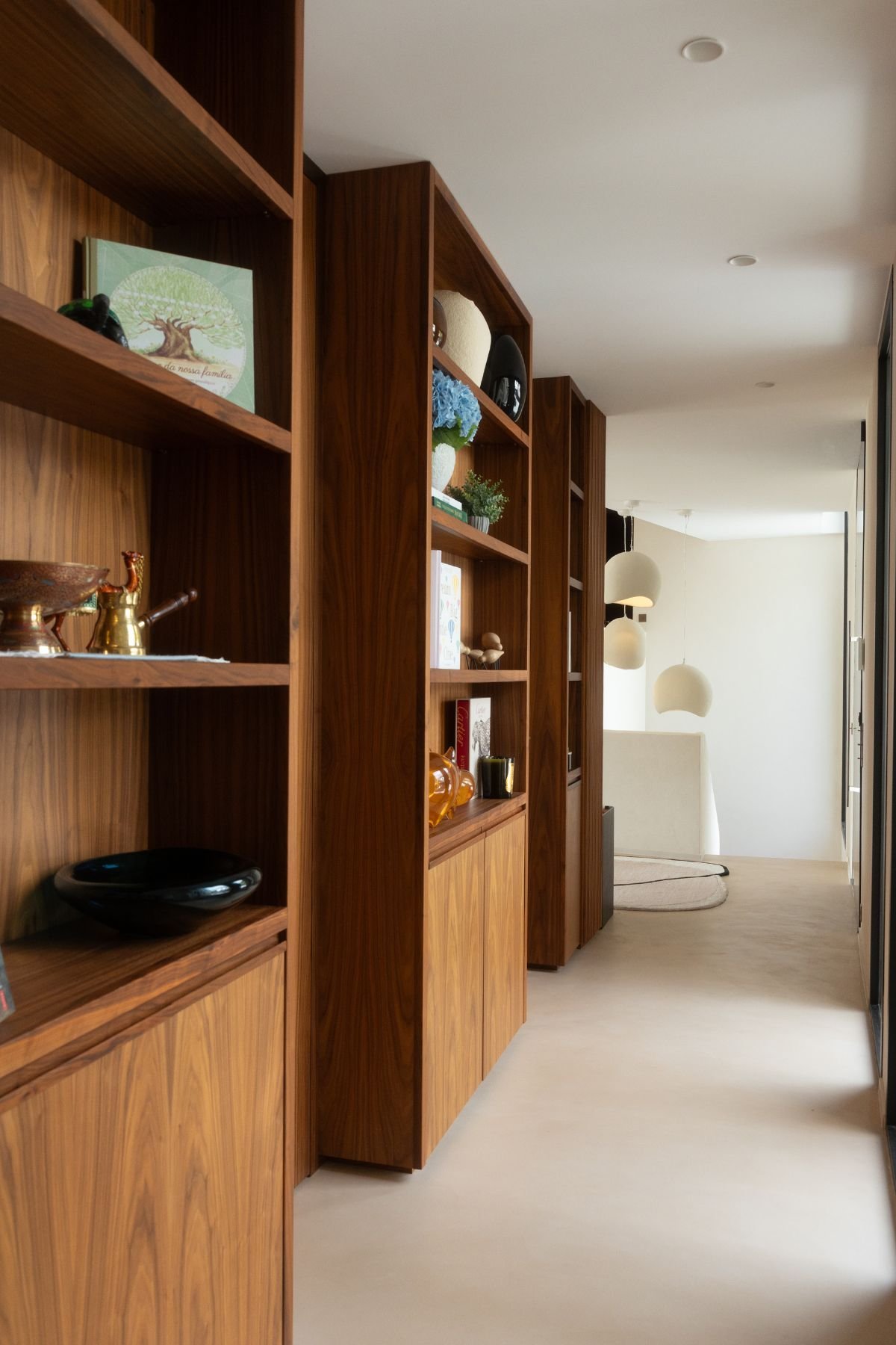 Corredor da casa moderna com estante madeira para livros e vasos decorativos a organizar a zona de passagem.