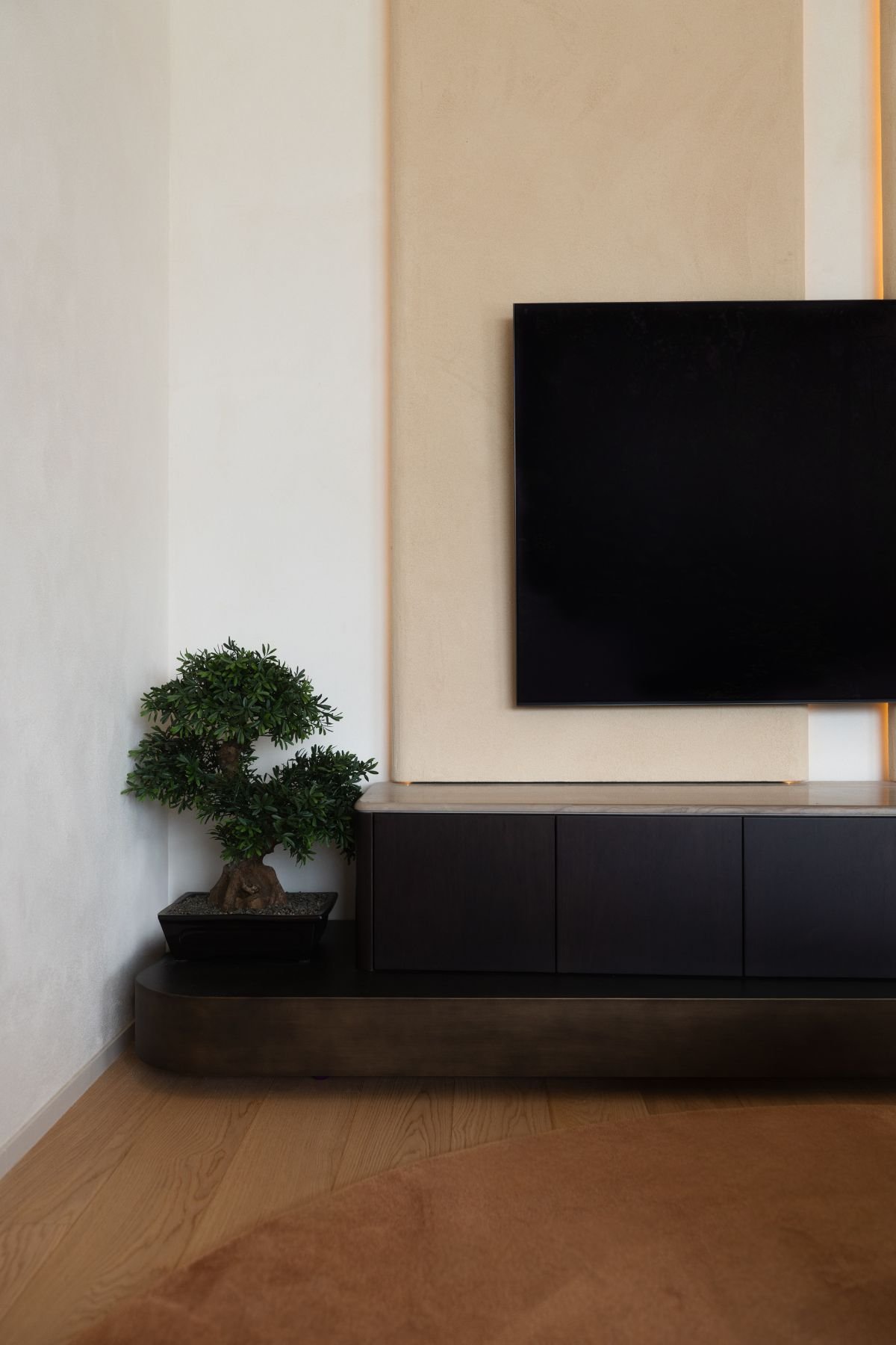 Móvel de sala para TV em tom escuro com móveis sala tv modernos e planta decorativa no canto do ambiente.