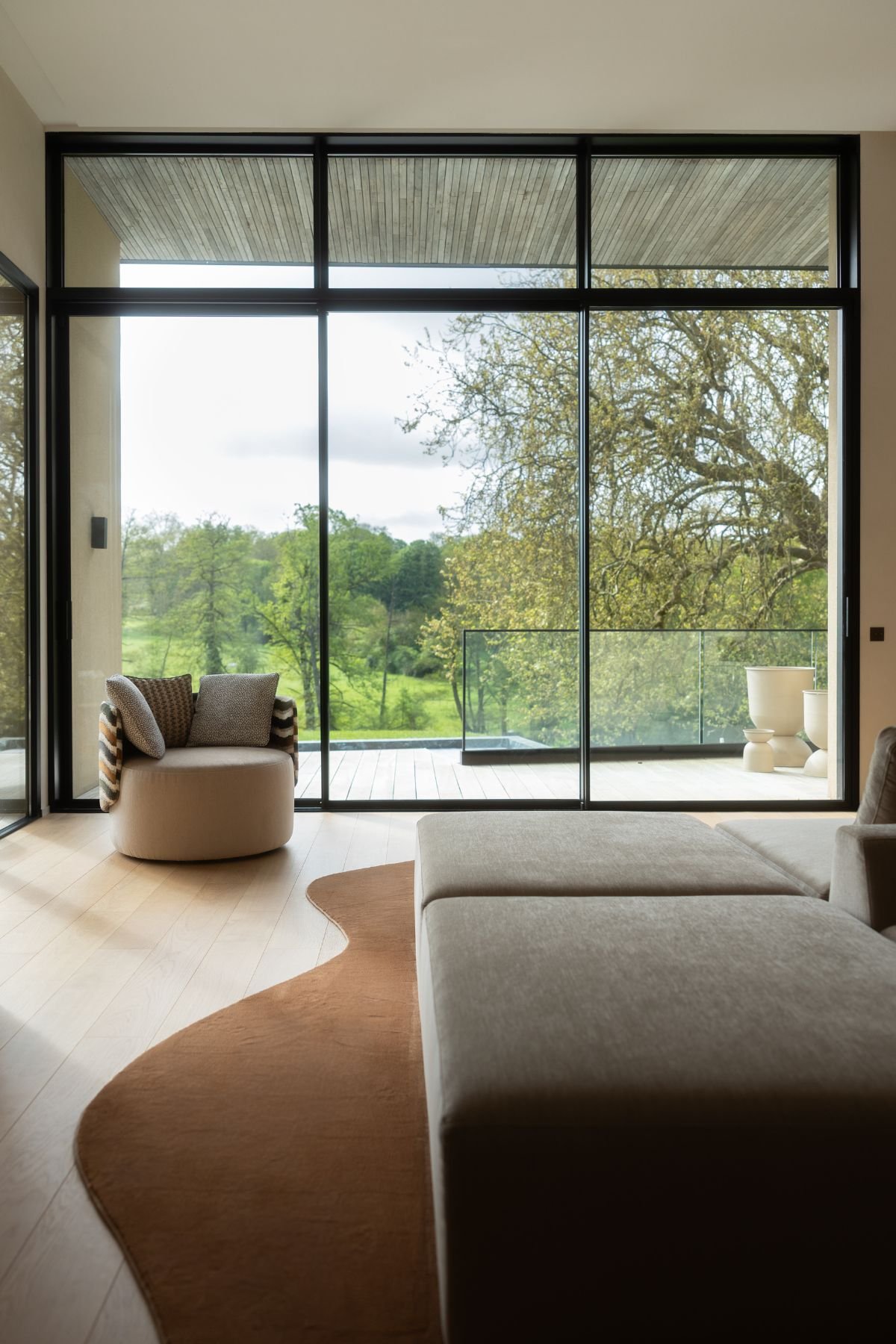Poltrona para sala posicionada junto às janelas de vidro com vista para o exterior da moradias de luxo.