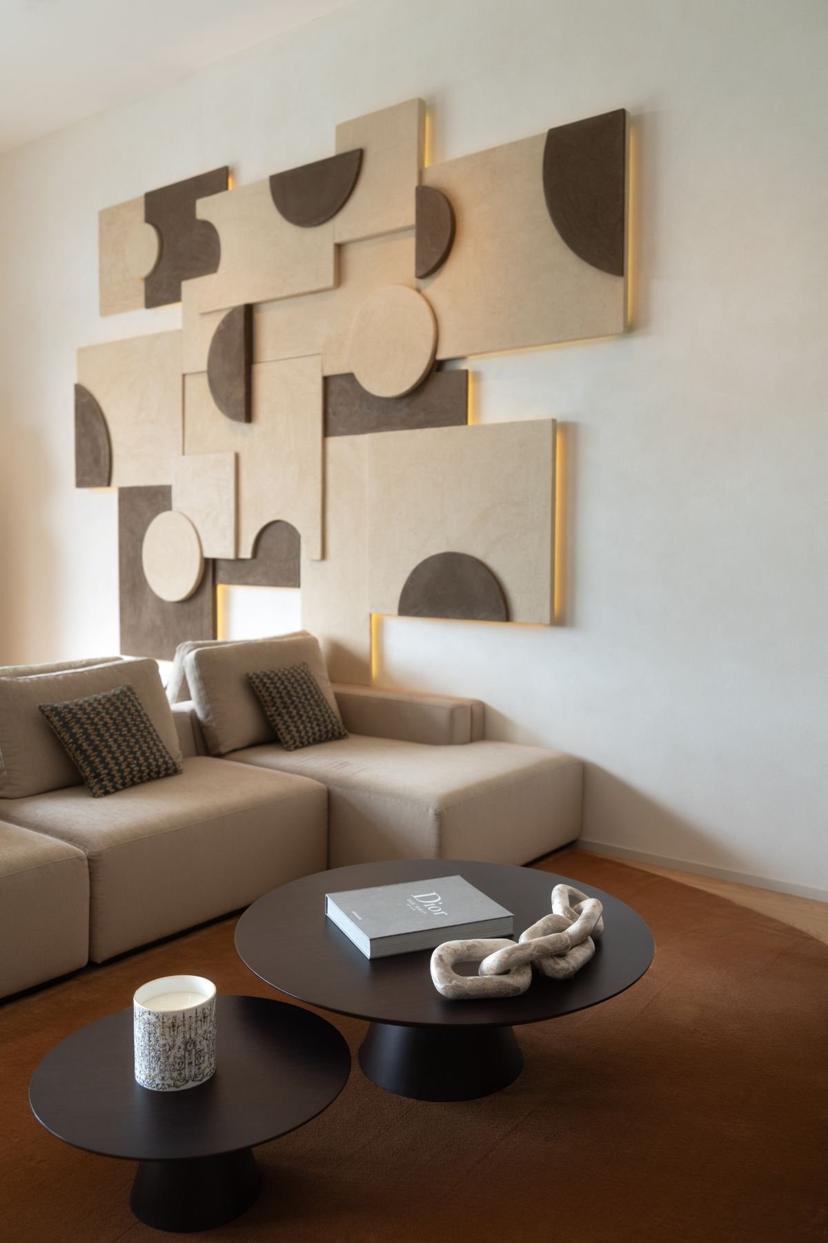 Mesa de centro sala em tom escuro com livro decorativo sobre o tapete da sala de estar moderna e sofá modular ao fundo.