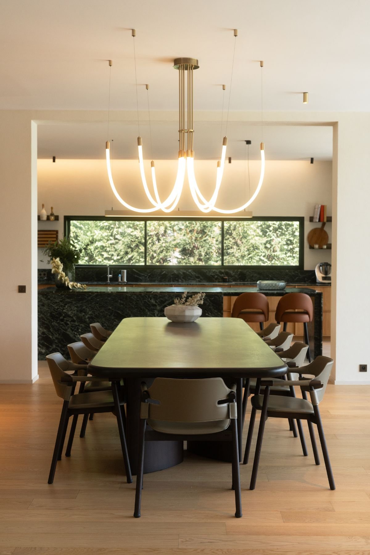 Mesa para sala de jantar retangular rodeada por cadeiras de sala de jantar com vista para a zona de cozinha.