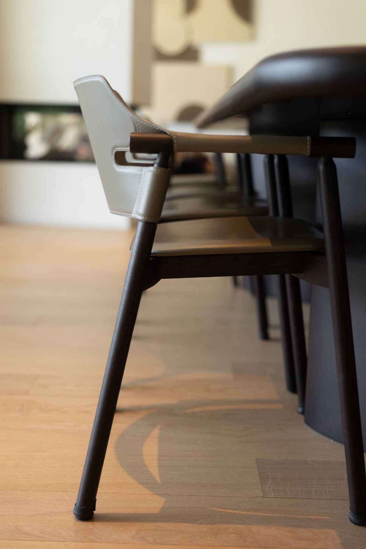 Detalhe lateral de uma cadeira de jantar em pele bege junto à mesa de jantar sala.