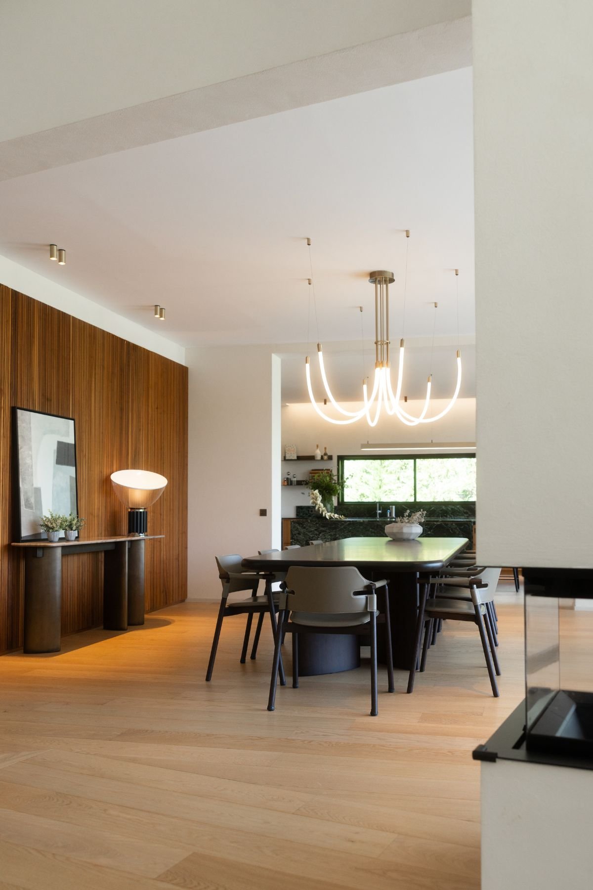 Espaço em open space com mesa para sala de jantar, cadeiras de sala de jantar em pele e iluminação suspensa.