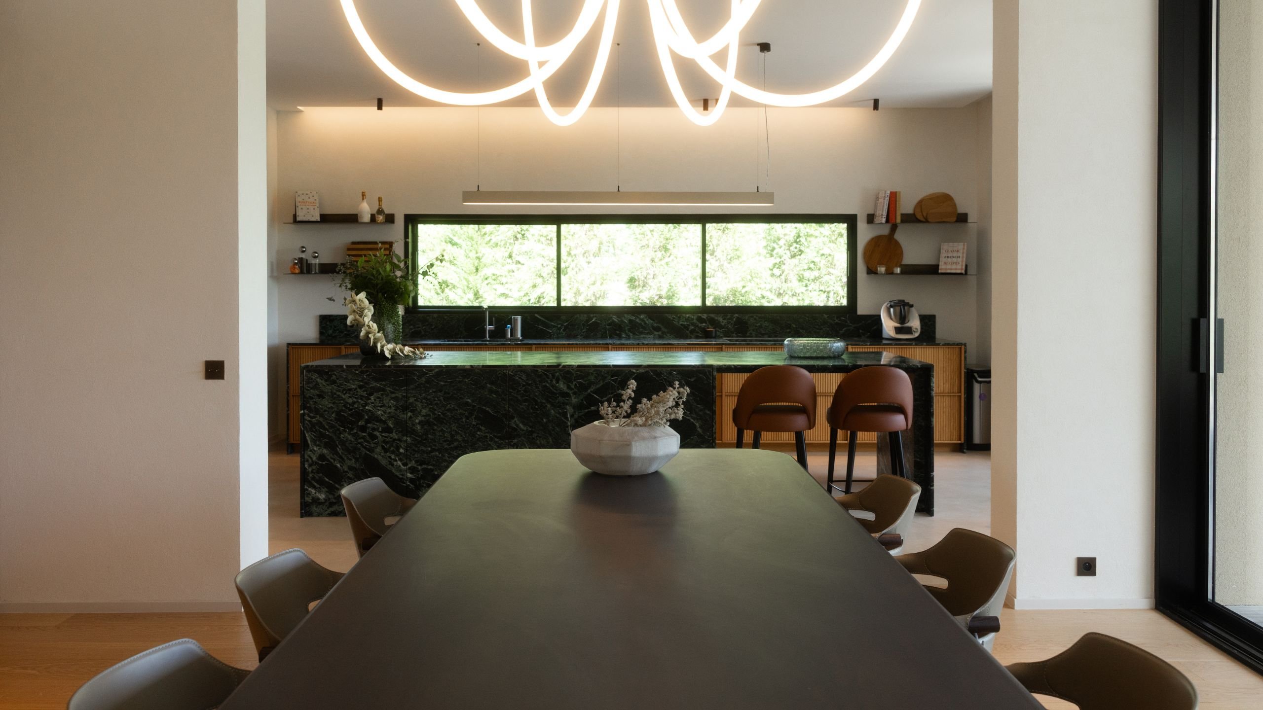 Open space integrando a mesa sala de jantar em primeiro plano e a cozinha com ilha moderna ao fundo.