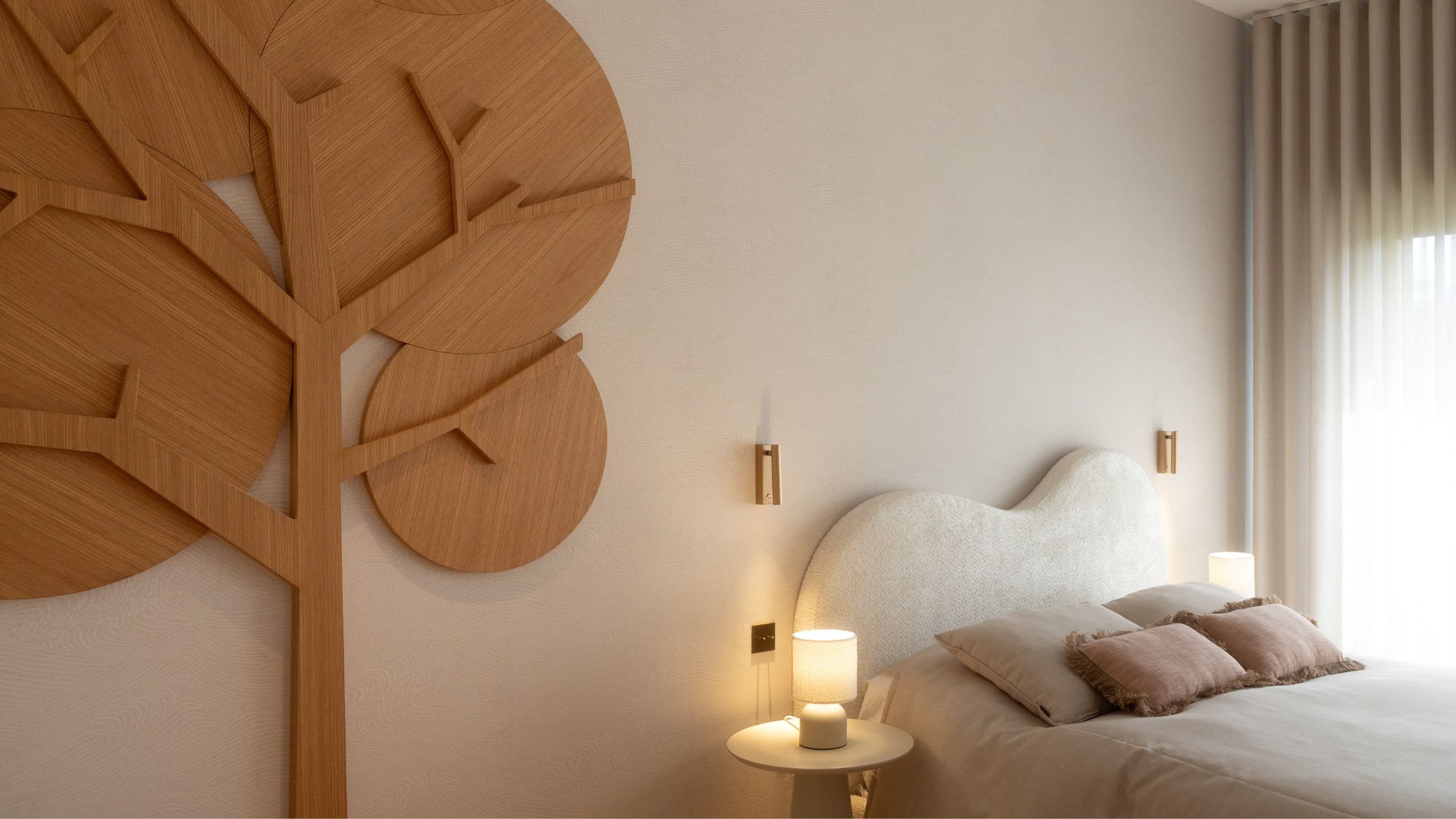 Decoração de quarto de criança com cama de casal de cabeceira orgânica estofada em boucle, mesa de cabeceira redonda e painel em formato de árvore.