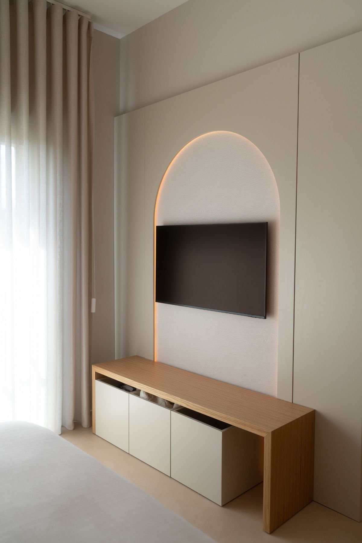Móvel para quarto infantil com bancada de TV e nicho em arco retroiluminado na parede.