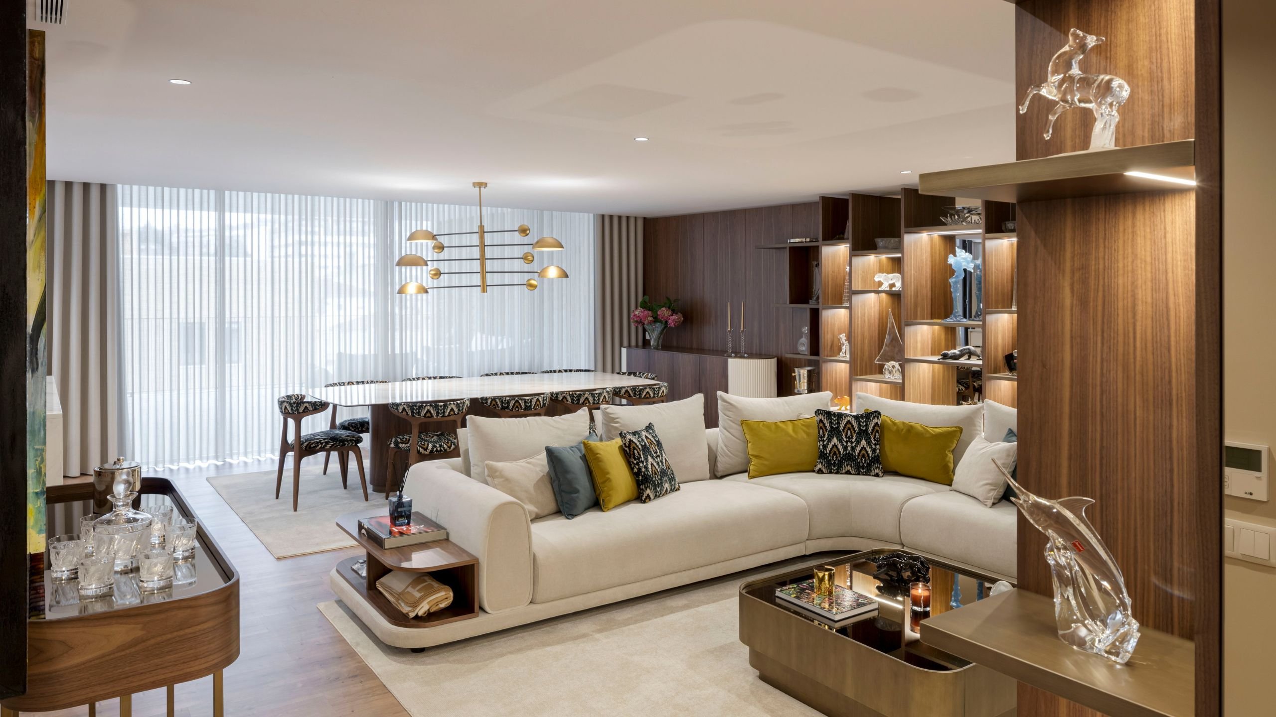 Sala de estar moderna integrada com sala de jantar, sofá claro, mesa Elea com cadeiras Bevel e aparador Club.