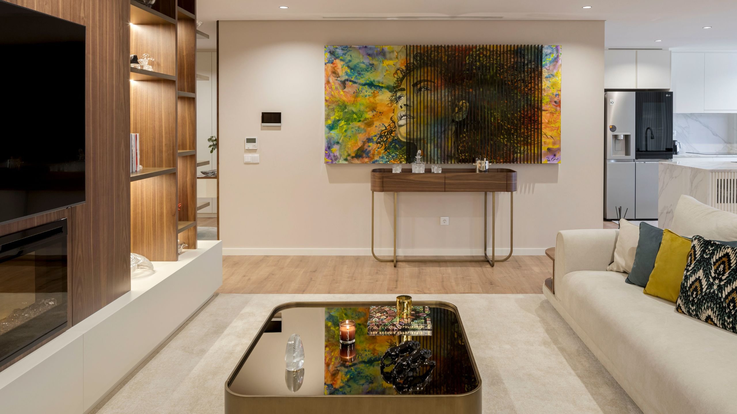 Sala de estar moderna com mesa de centro His, consola em madeira, quadro vibrante e painel de TV com lareira.