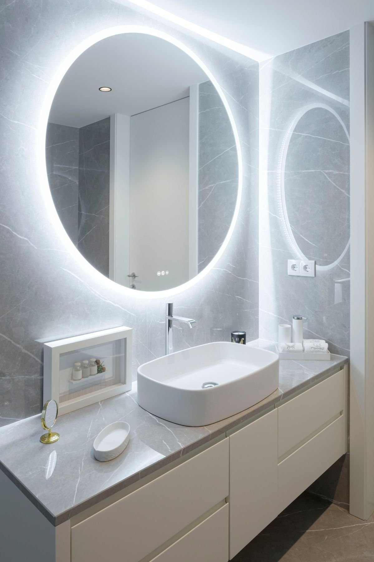Casa de banho privada do quarto de hóspedes com lavatório de pousar retangular, móvel suspenso e espelho circular retroiluminado.