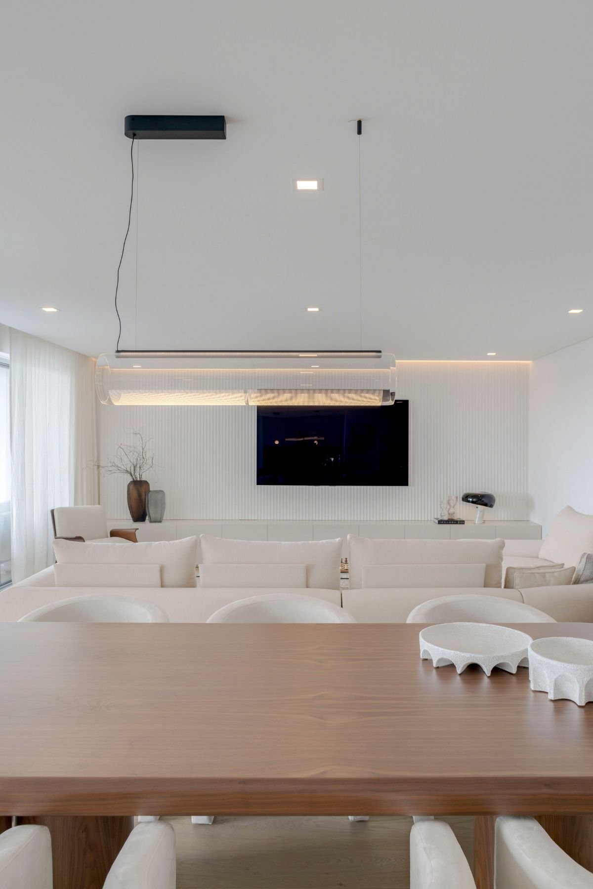 Decoração sala de estar e jantar em conceito aberto, destacando a mesa de jantar em carvalho Natur e painel de TV ao fundo.