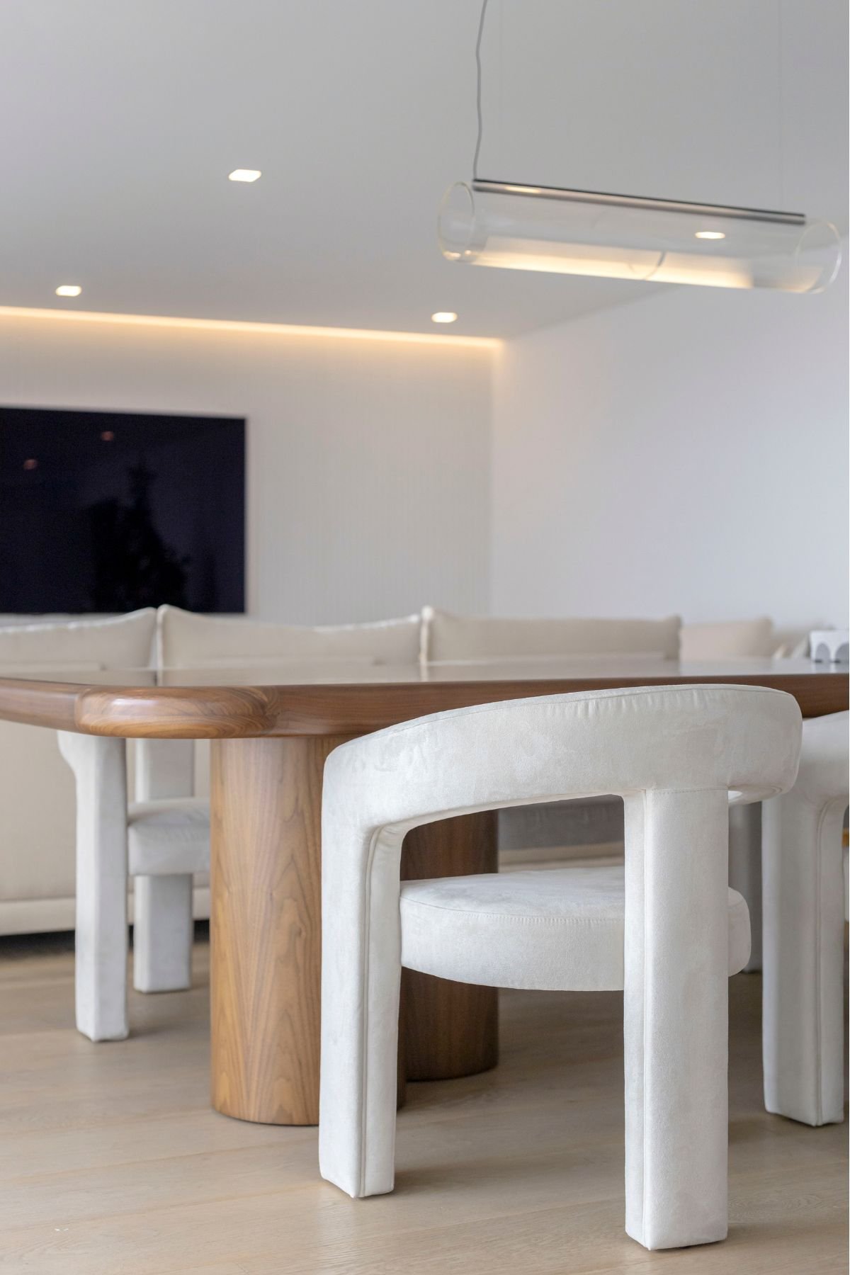 Detalhe das cadeiras de jantar estofadas a creme e do pé em madeira da mesa de jantar.