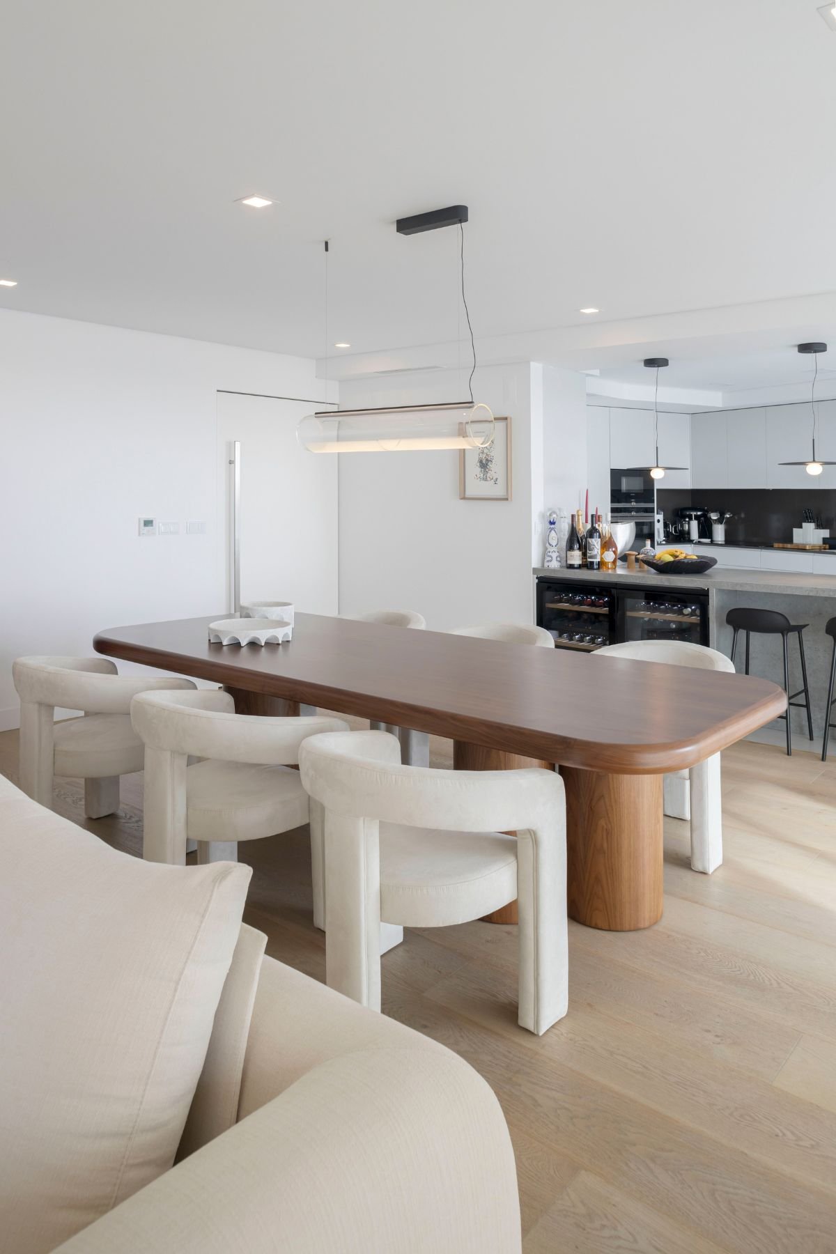 Perspetiva da sala de jantar em conceito aberto integrada com a cozinha moderna e a ilha com garrafeira.