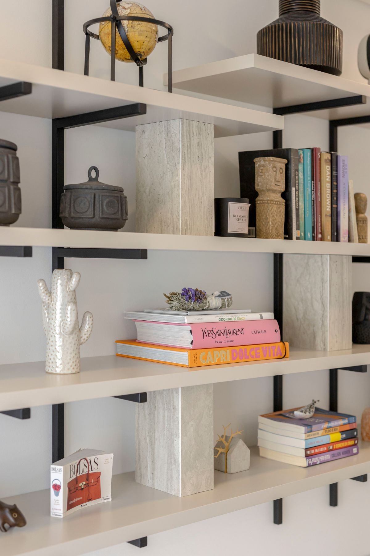 Pormenor dos nichos e prateleiras da estante Natur com livros e peças decorativas.