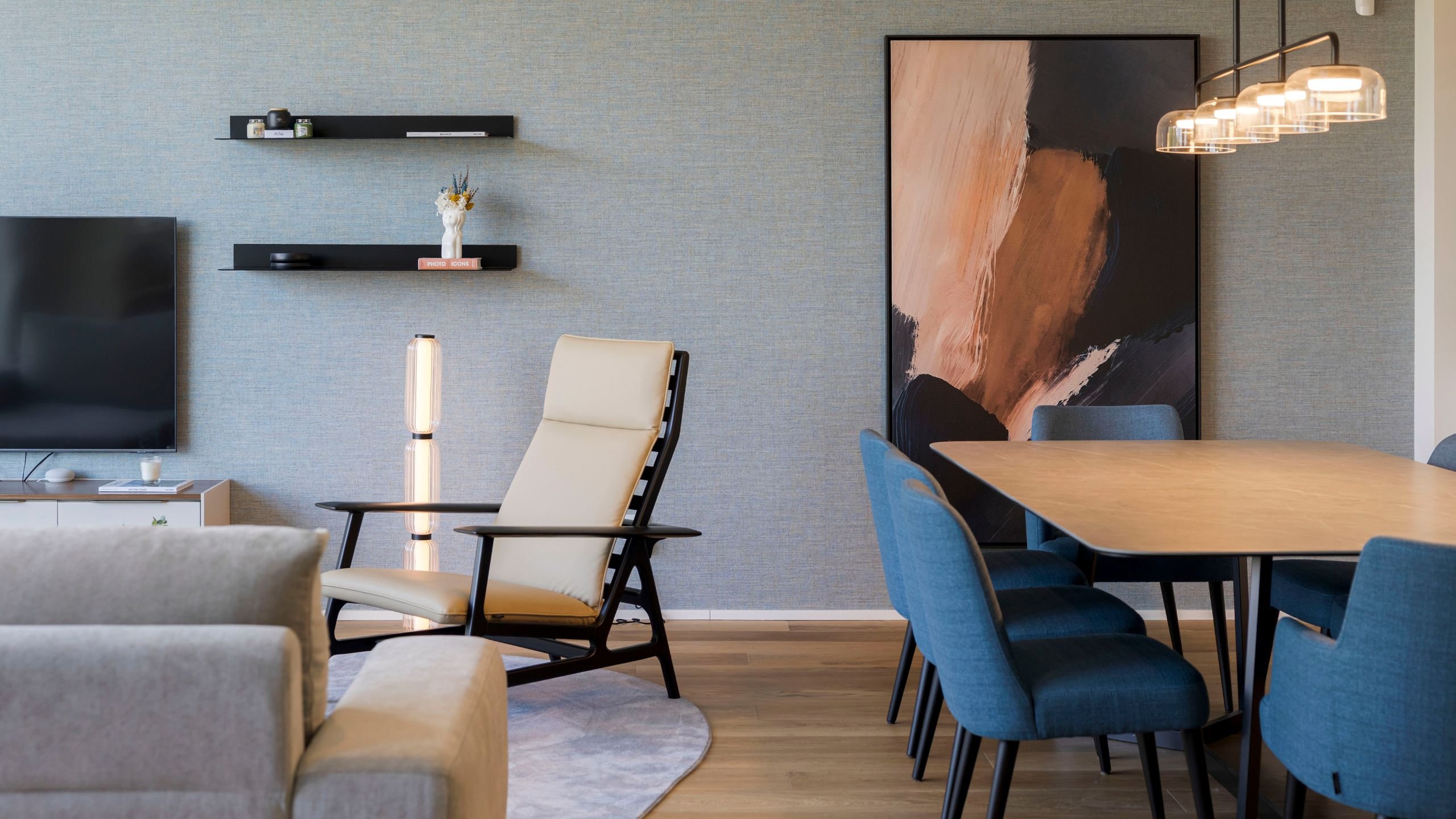 Open space com sala de estar moderna, um cadeirão confortável junto a um candeeiro de pé e uma mesa de sala jantar elegante.