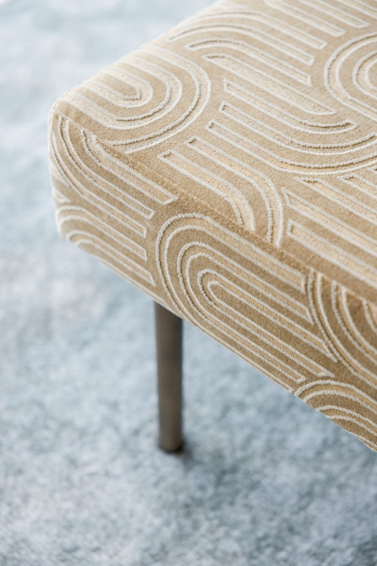 Pormenor do tecido com padrão orgânico e textura da banqueta aos pés da cama.
