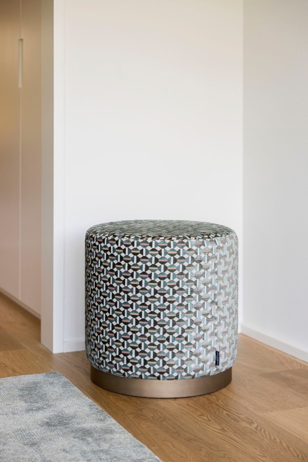 Pormenor do pufe com estofos geométricos e base metálica, perfeito para complementar a decoração do quarto.